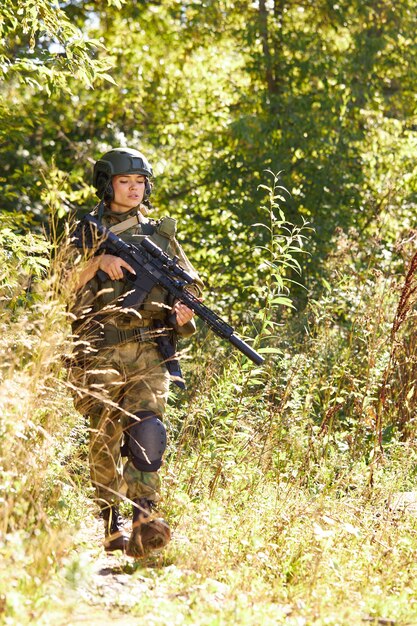 Foto ritratto di giovane donna con arma in abbigliamento militare all'aperto