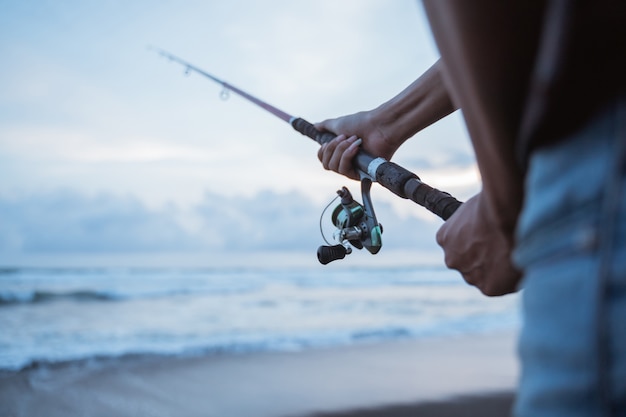 Foto ritratto di un giovane pescatore che pesca da solo sulla spiaggia