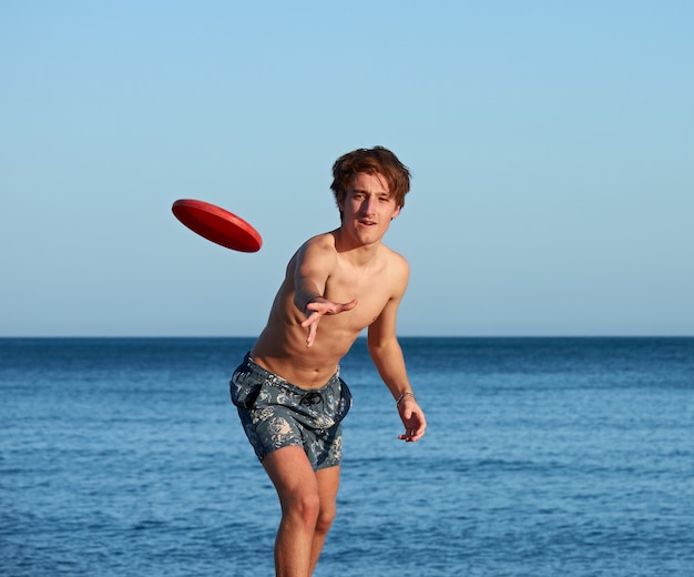 A portrait of a young fit caucasian male playing frisbee in the beach