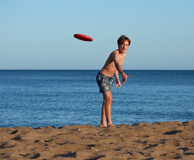 A portrait of a young fit caucasian male playing frisbee in the beach