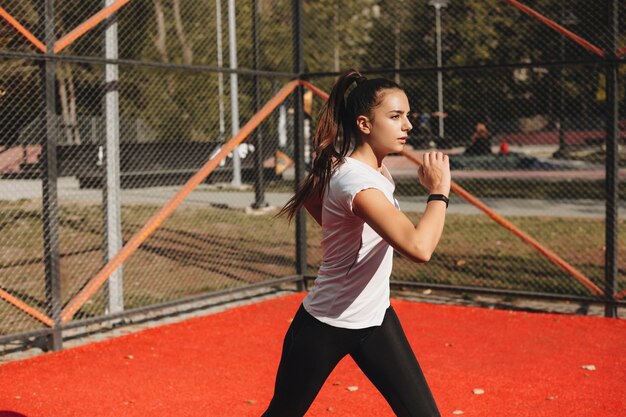 スポーツパークで朝のスポーツルーチンをしている若いフィット女性の肖像画。