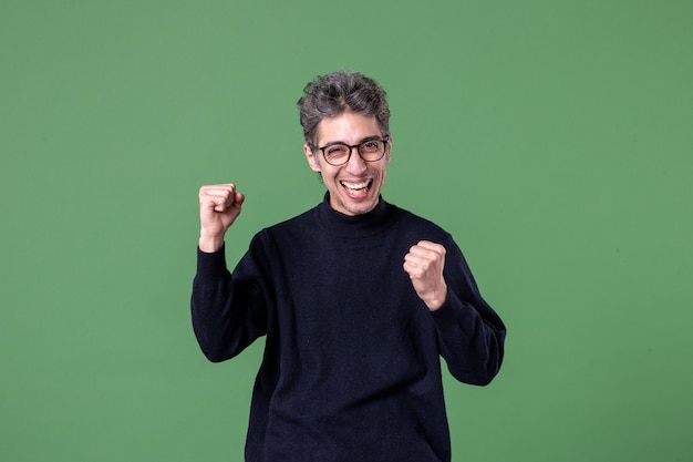 Portrait of young genius man dressed casually in studio shot happy on green wall