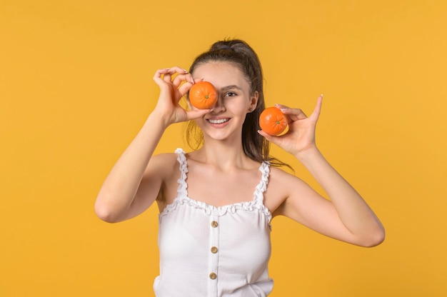 Portrait of a young girl covering her eyes with tangerine