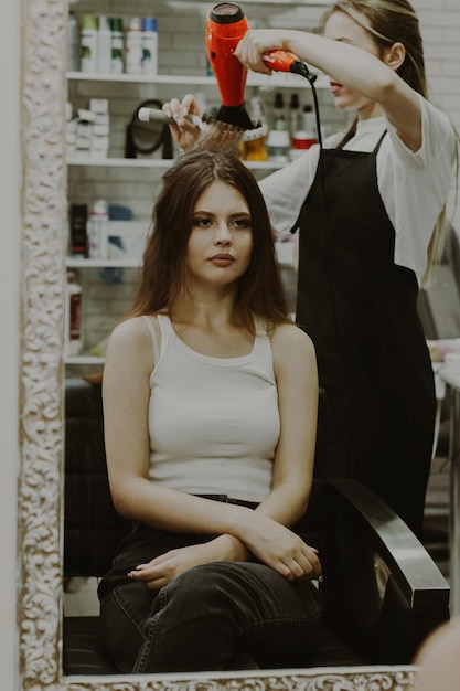 Photo portrait of a young girl doing her hair at the hairdresser