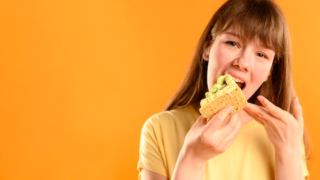 Portrait of young girl eating cake with copy space