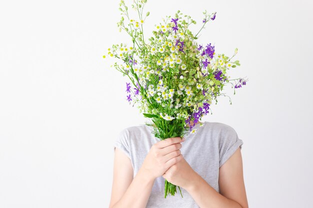 A portrait of a young girl in gray clothes who hid her face behind a bouquet of purple