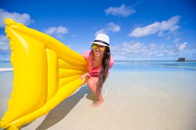 Portrait of young girl having fun with air mattress in swimming pool