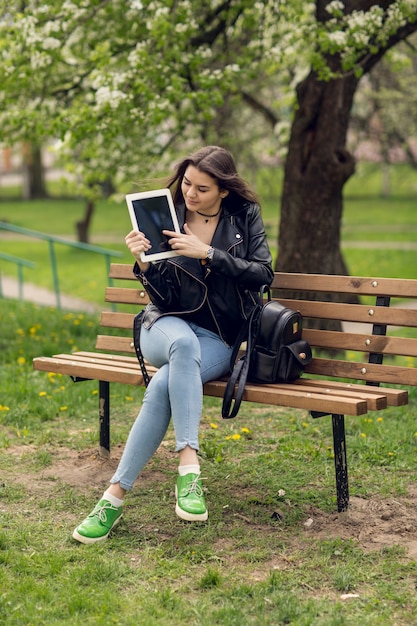 Portrait of young girl holding digital tablet in the park