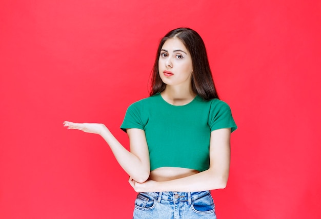 Portrait of young girl holding open space on red background. 