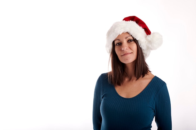 Portrait of a young girl looking at the camera with a Santa Claus hat on a white background.