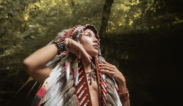 Photo portrait of a young girl in native american headdresses against the background of nature