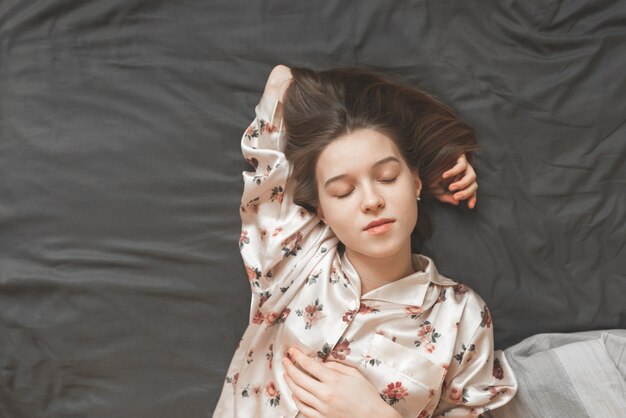 Photo portrait of a young girl in a pajama sleeping on the bed
