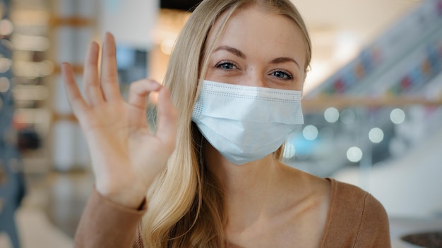 Portrait of young girl in protective medical mask caucasian woman showing sign okay joyful blonde