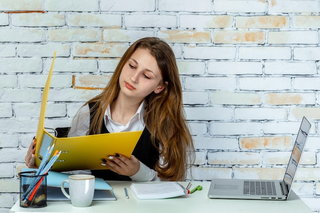 Портрет молодой девушки, сидящей за столом и читающей свои заметки