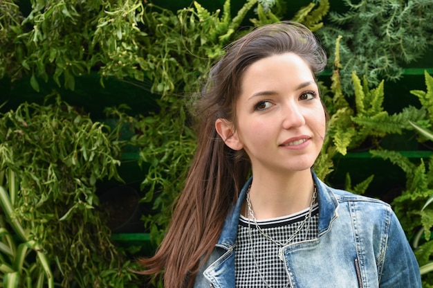 Portrait of a young girl on a space of green plants