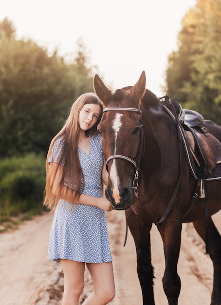 笑顔のカメラを見ている馬の横に立っている若い女の子の肖像画。