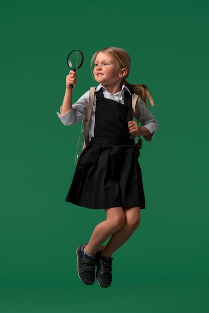 Foto ritratto di una giovane studentessa in uniforme scolastica che salta a mezz'aria