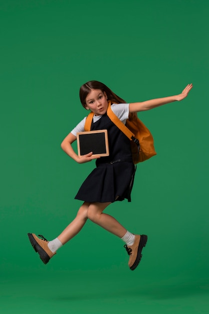 Foto ritratto di una giovane studentessa in uniforme scolastica che salta a mezz'aria