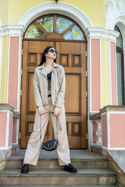 Portrait of young girl in stylish white clothes posed against door at old house