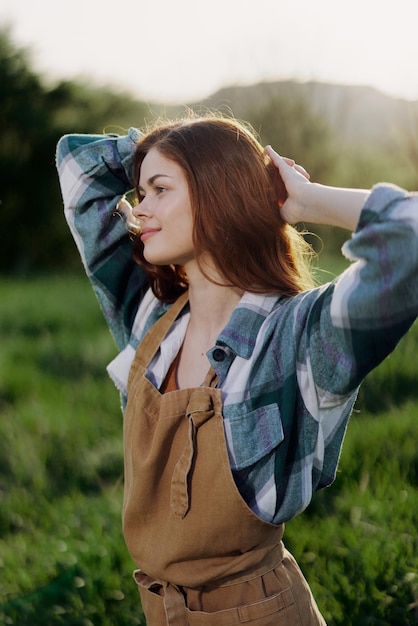 Portrait of a young girl on a summer day in the rays of the setting sun with a beautiful smile dressed as a farmer and gardener