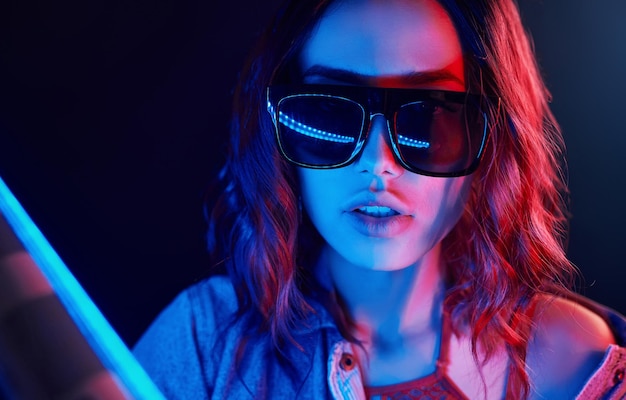 Portrait of young girl in sunglasses in red and blue neon in studio