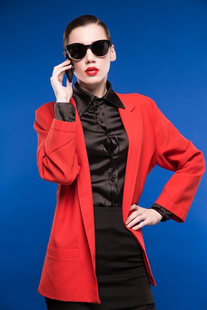 Portrait of a young girl in sunglasses and with a phone in his hand