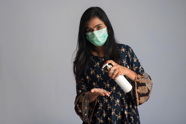 Portrait of young girl using or showing a sanitizing gel from a bottle for hands cleaning.