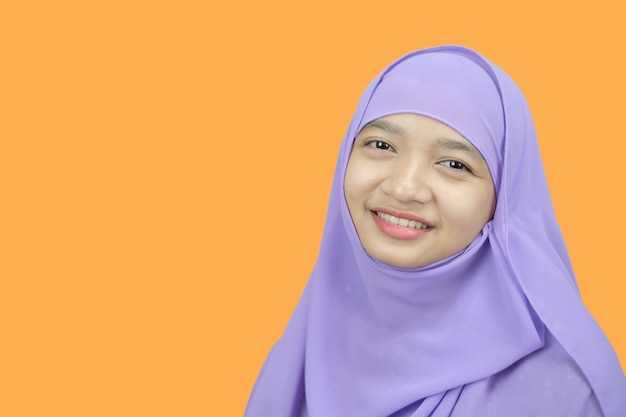 Portrait young girl wear purpel hijab on orange background.