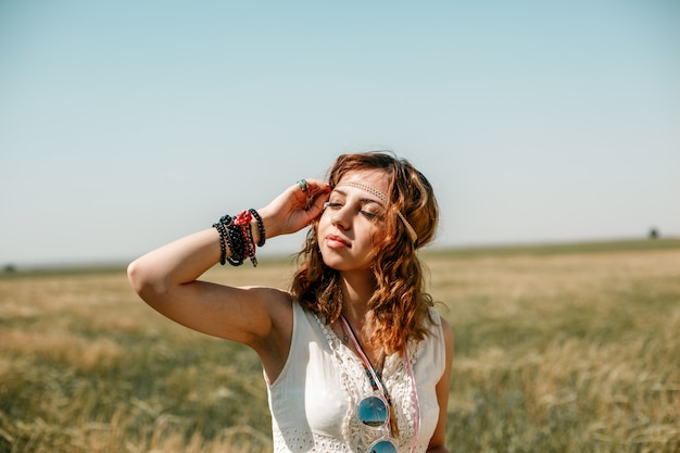 Portrait of a young girl in a white translucent dress in boho or hippie style