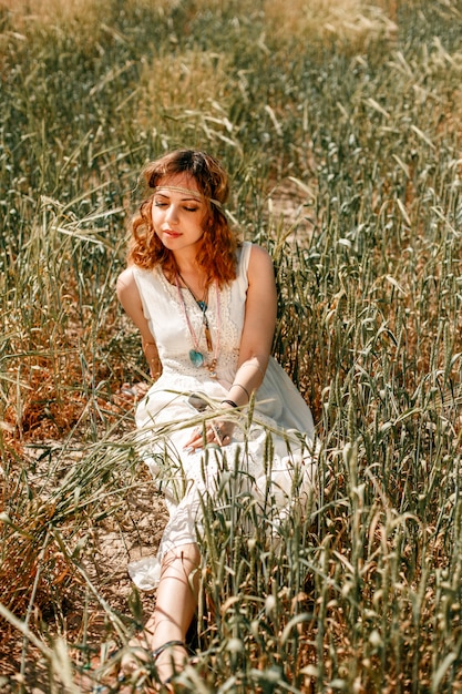 Portrait of a young girl in a white translucent dress in boho or hippie style