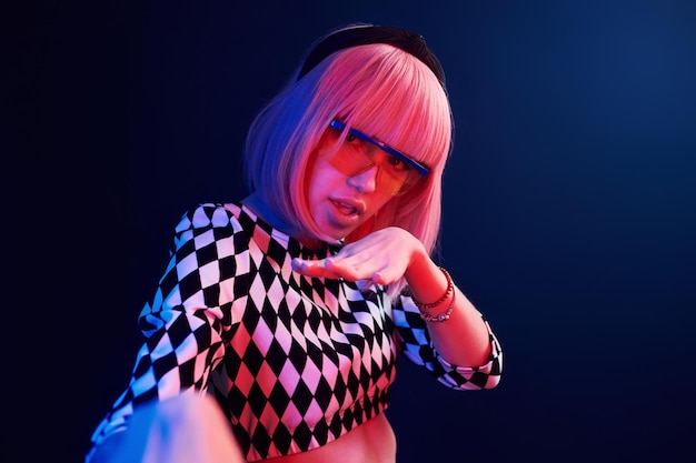 Portrait of young girl with blond hair in eyeglasses in red and blue neon in studio