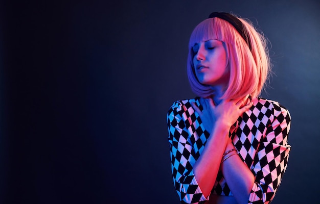 Portrait of young girl with blond hair in red and blue neon in studio