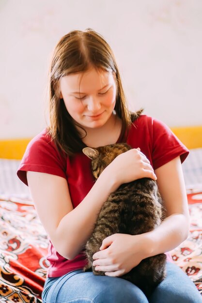 Photo portrait of young girl with cat sitting on sofa at home