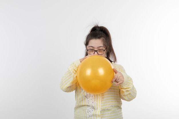 Photo portrait of young girl with a down syndrome wearing yellow checkered shirt holding air balloon