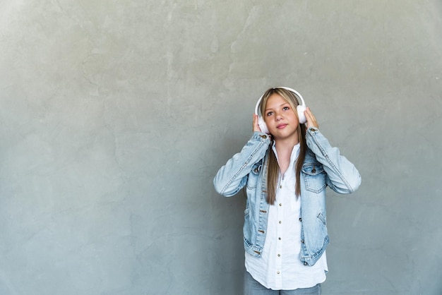 Portrait of a young girl with headphones on a gray background