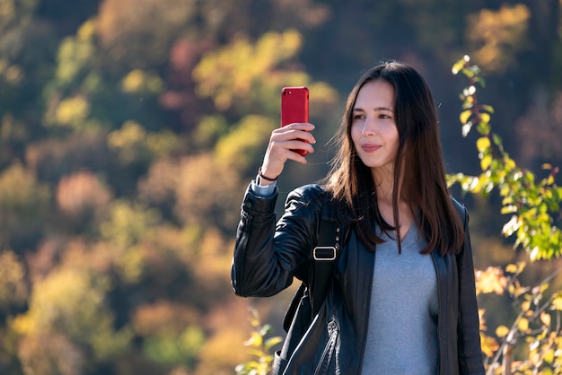 屋外の手で携帯電話を持つ少女の肖像画