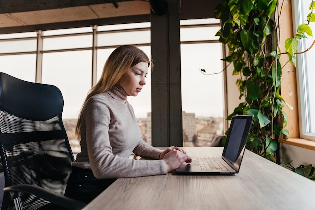 Portrait of a young girl working on a laptop sitting in a modern coworking space