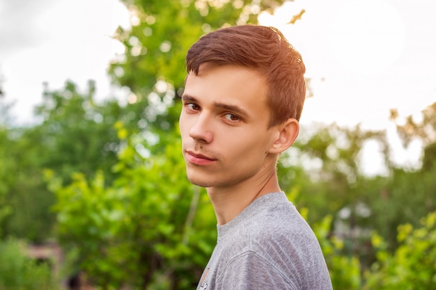 Portrait of a young guy on a natural green background