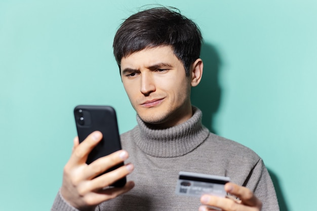 portrait of young guy using smartphones and credit card