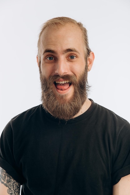 Foto ritratto di un giovane ragazzo con la barba in una maglietta nera su sfondo bianco hipster