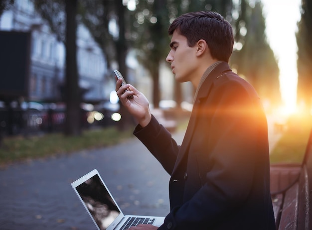 彼の手に携帯電話を持つ若い男の肖像画。男は街を歩き回る。