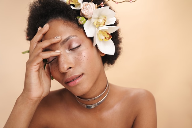 彼女の髪に花を持つ若い半裸のそばかすアフリカ系アメリカ人女性の肖像画