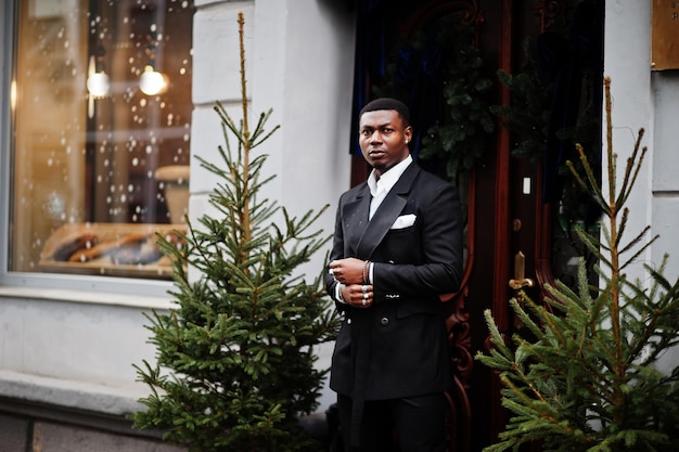 Portrait of young and handsome african american businessman in suit near new year tree decorations