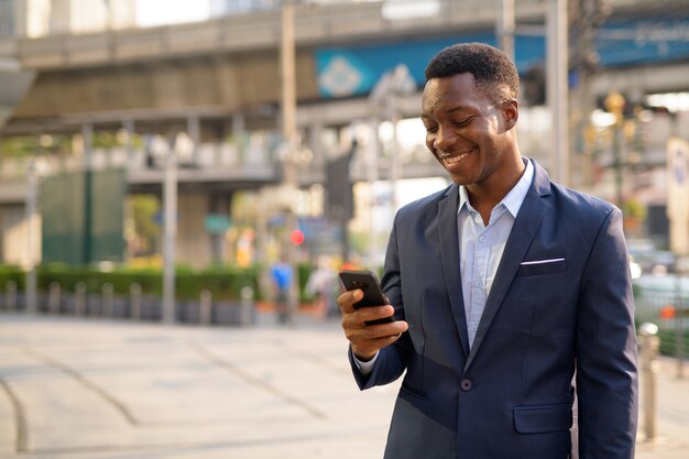 Portrait of young handsome African businessman exploring the city streets of Bangkok