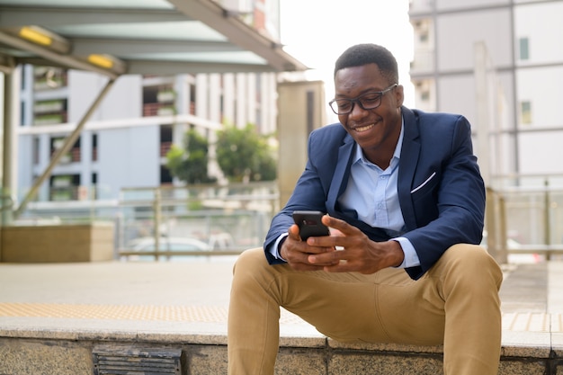 Portrait of young handsome African businessman outside the subway train station