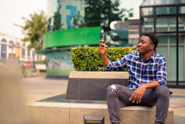 Portrait of young handsome African man at the park in the city outdoors