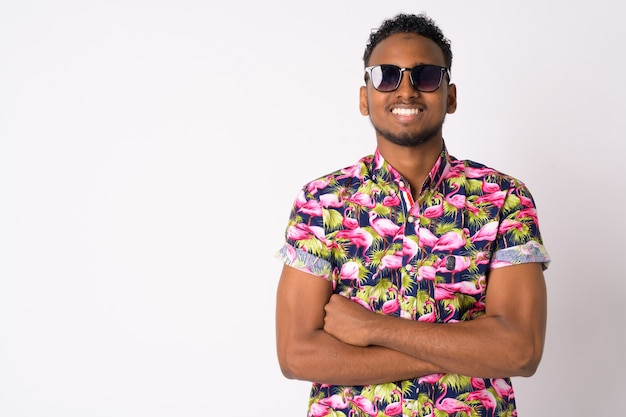 Portrait of young handsome African tourist man against white wall