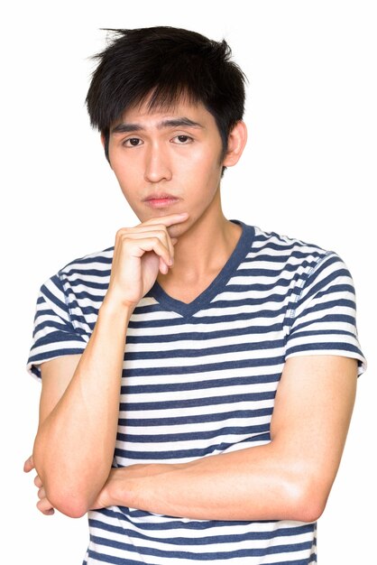 Portrait of young handsome Asian man isolated against white wall