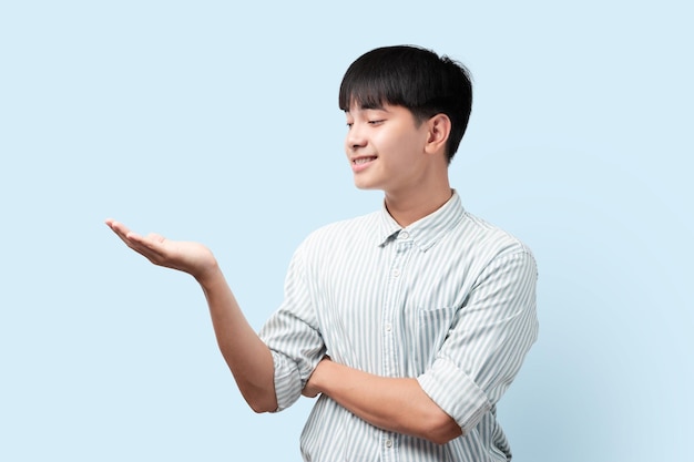 Ritratto di giovane uomo asiatico bello mostra porgere la mano con il palmo uomo asiatico in piedi sul blu