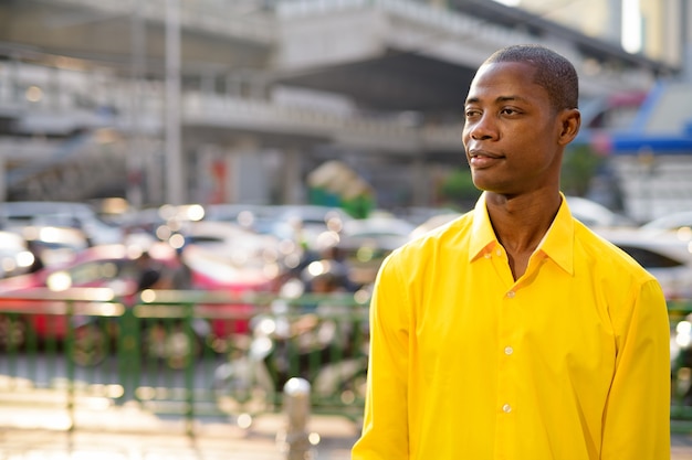 Портрет молодого красивого лысого африканского бизнесмена, изучающего городские улицы Бангкока